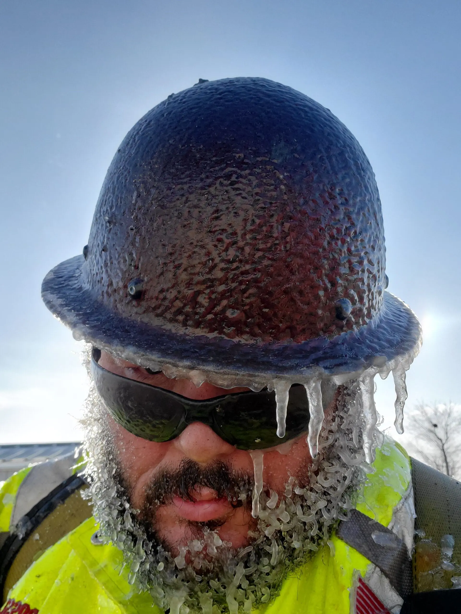 A construction working wearing a hat covered in ice.