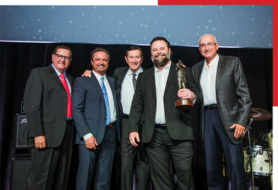 A group of men posing for a picture with an award.