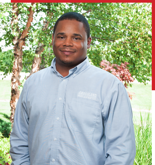 A man in a blue shirt standing in front of a tree.
