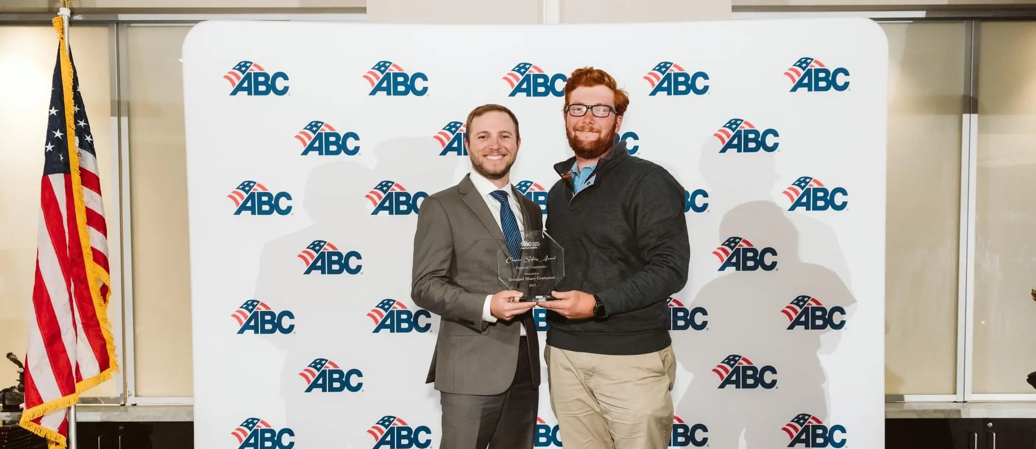 Two men posing for a picture in front of an ABC logo banner.