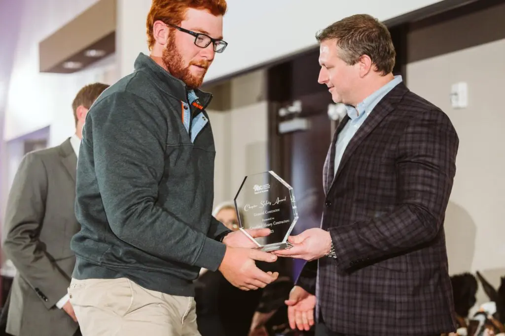 A man is handing an award to another man.