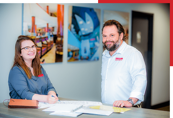 A man and woman standing in front of a desk.