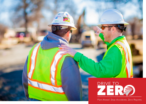 Two construction workers wearing PPE outside.