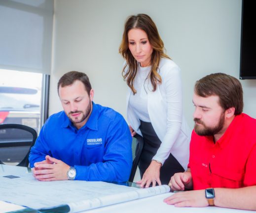 A group of people sitting around a table looking at blueprints.