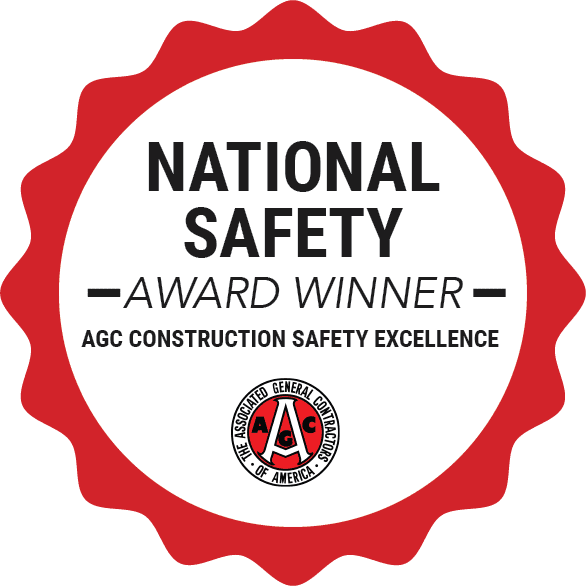 A red and white badge with the text "National Safety Award Winner, AGC Construction Safety Excellence" and the Associated General Contractors of America logo at the bottom.