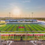 A view of a football field with a stadium in the background.