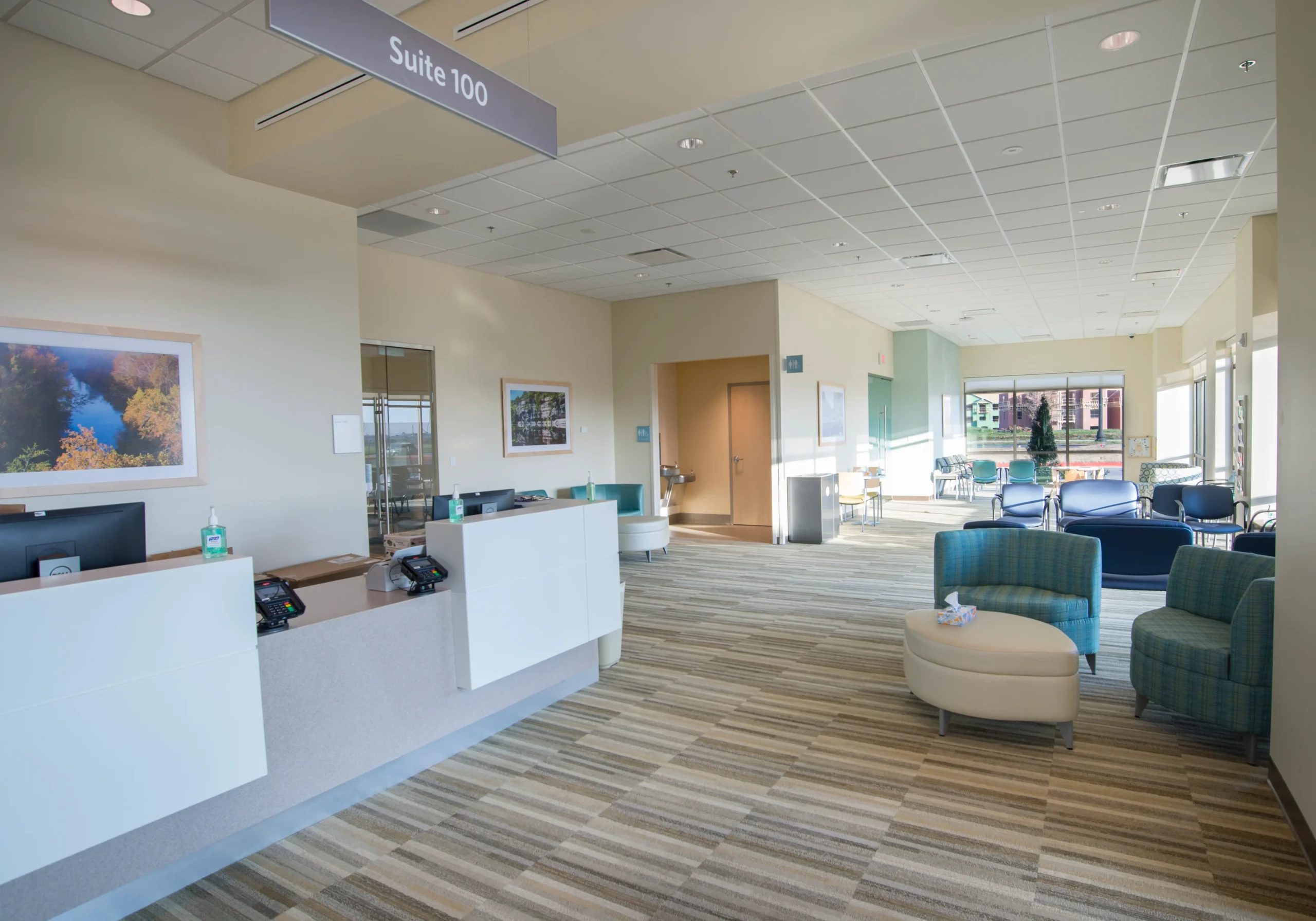 A reception area with a blue chair and a white desk.