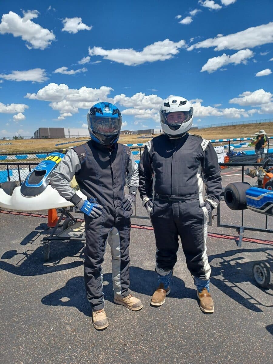 Two Crossland interns in racing suits at a go-kart track for Intern Day