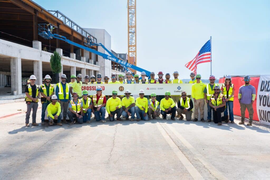Crossland crew and project partners gathered around the signed final steel beam at a topping-out ceremony.
