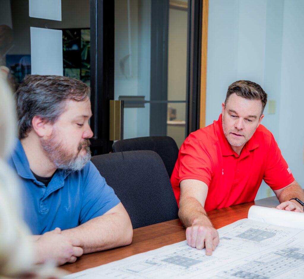 Two Crossland team members at a conference table talking through a set of construction drawings.