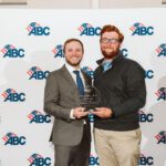 Two men posing for a picture in front of an ABC logo banner.
